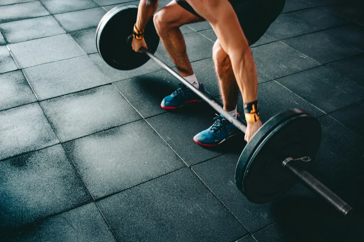A lifter setting up a loaded barbell deadlift on a gym floor